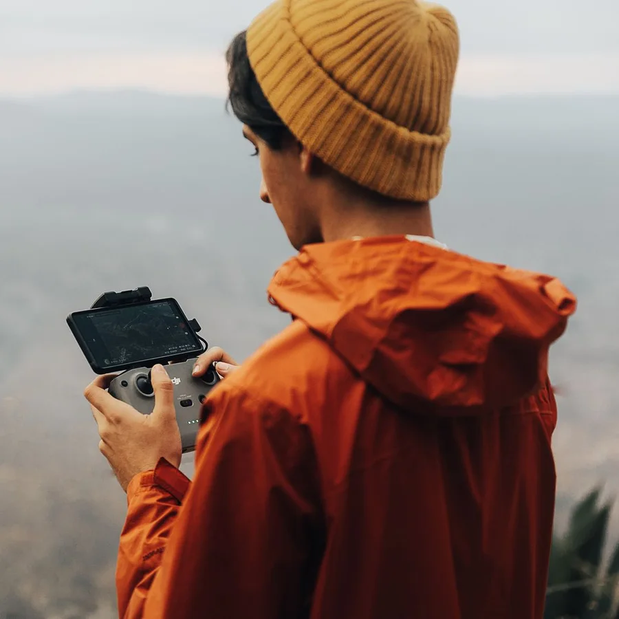 Pilot flying a drone on a hillside at golden hour